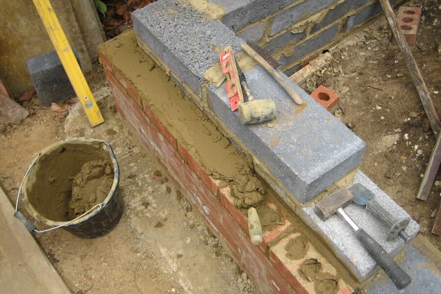 Mason laying red clay bricks and inspecting uniform alignment